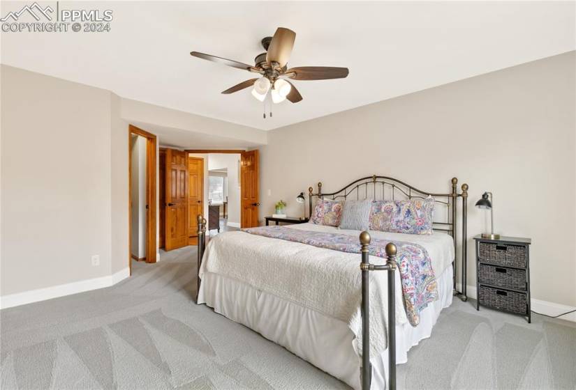 Main level bedroom with ceiling fan, walk-in closet and attached bath.
