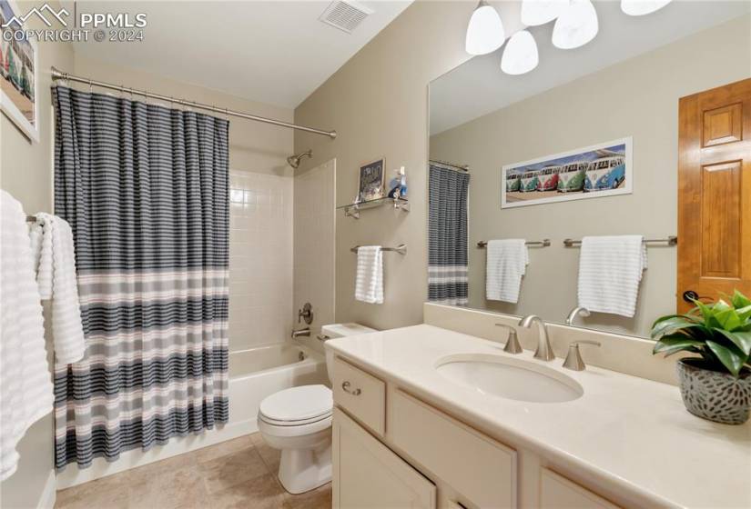 Upper level full bathroom with oversized vanity, toilet, shower / tub combo, and tile floors