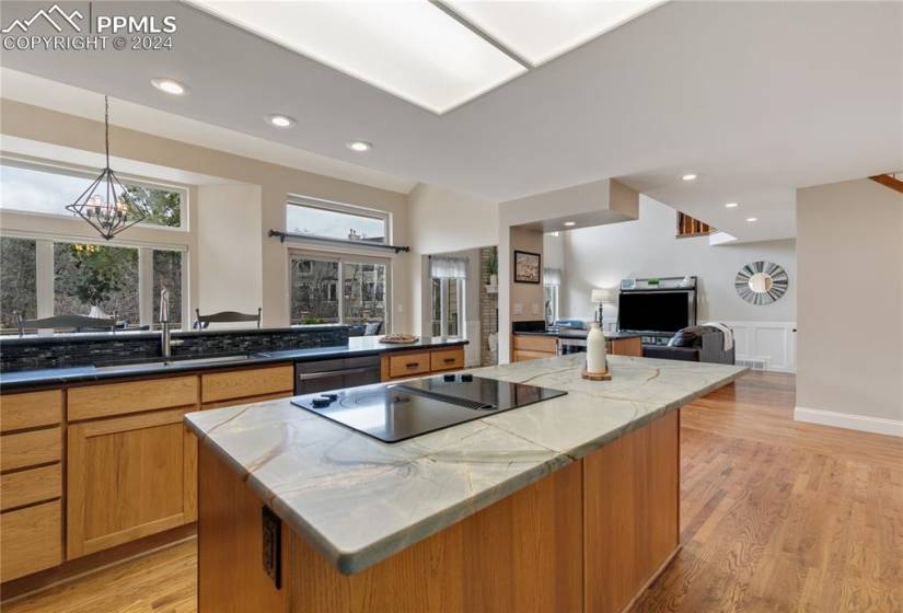 Kitchen with black electric cooktop, sink, light hardwood / wood-style flooring, a center island, and pendant lighting