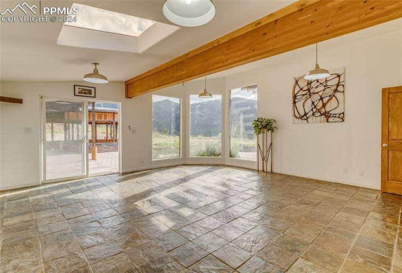 Empty room with light tile floors, a skylight, and a mountain view