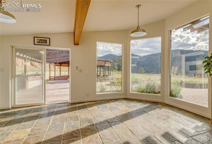 Unfurnished sunroom featuring lofted ceiling with beams and a mountain view