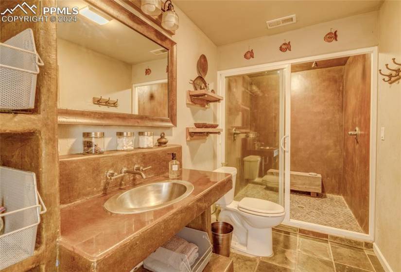 Bathroom featuring vanity, tile flooring, toilet, and tiled shower