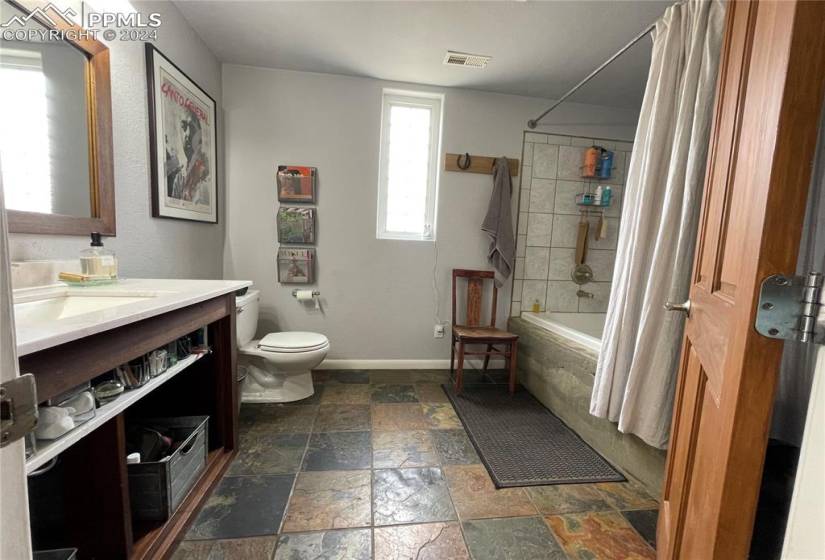 Full bathroom featuring vanity, shower / bath combination with curtain, toilet, and a healthy amount of sunlight