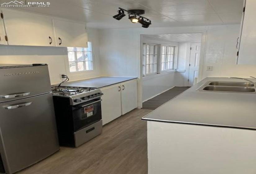 Kitchen featuring appliances with stainless steel finishes, white cabinetry, vinyl plank flooring, and sink