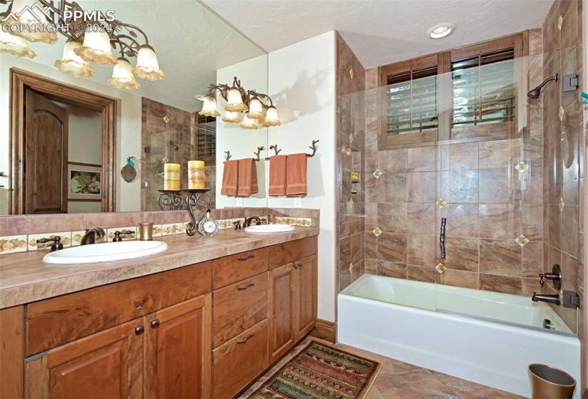 Bathroom with double sink, tiled shower / bath, tile floors, a chandelier, and oversized vanity