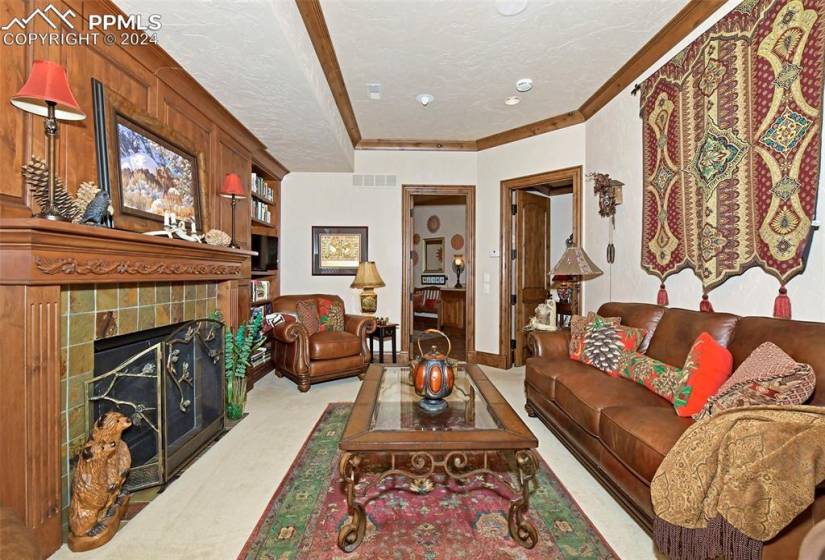 Living room featuring a tile fireplace, ornamental molding, and light carpet