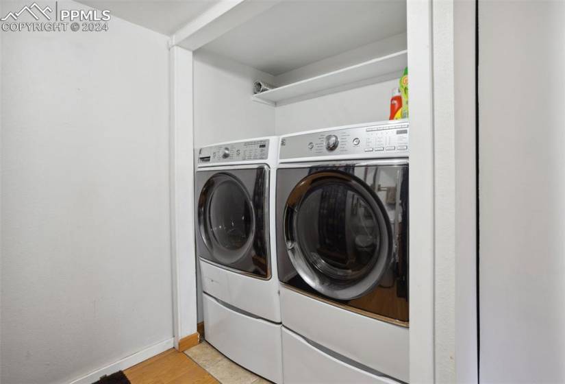 Clothes washing area featuring light tile floors and washer and clothes dryer