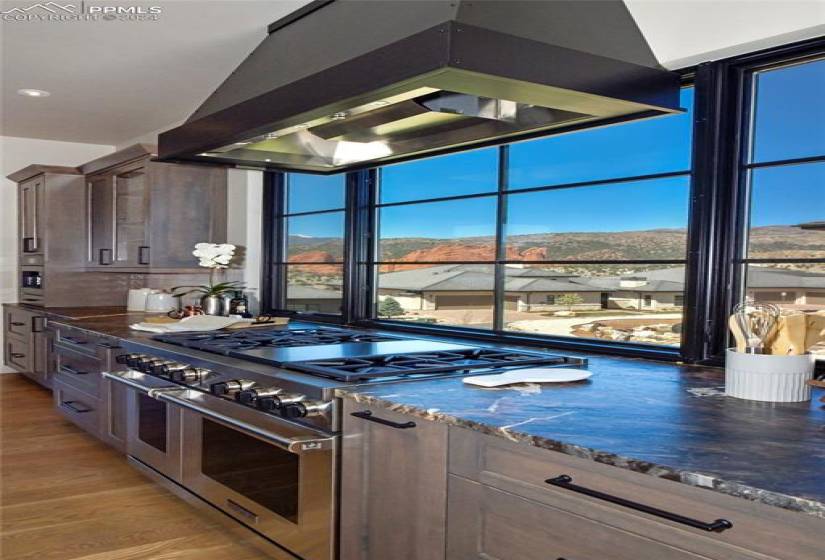 Kitchen featuring lots of Natural light with Amazing Views, Wolf double oven range, 6 Burner plus griddle Wolf cooktop, custom cabinets,large exhaust hood, and beautiful stone countertops