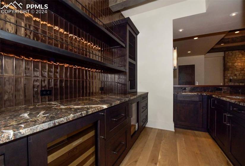 Bar featuring sink, light hardwood / wood-style flooring, dark stone countertops, and beamed ceiling