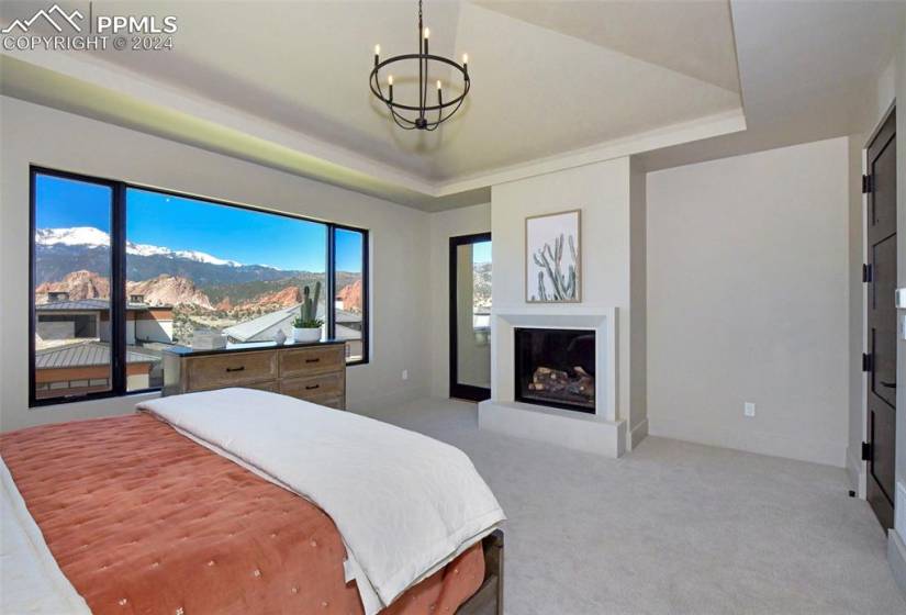 Master Bedroom featuring a mountain view, tray ceiling, in suite fireplace and walkout to private covered balcony.
