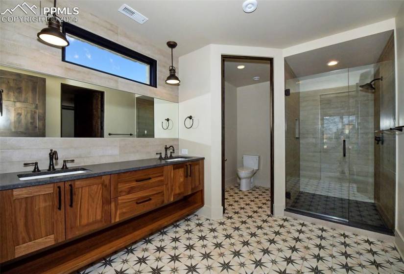 One of 3 Bathroom Lower Level Guest baths, thiis one features  walk in shower, backsplash, tile flooring, toilet, and double vanity