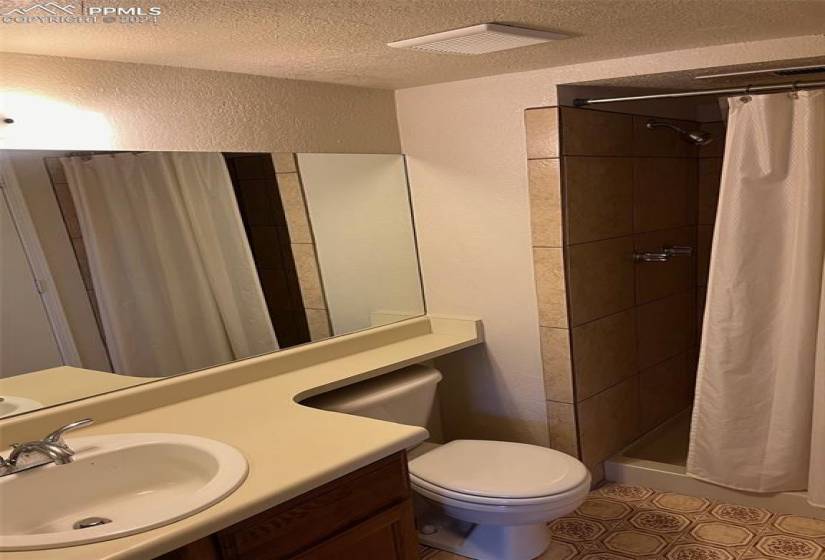 Bathroom featuring toilet, a shower with shower curtain, a textured ceiling, vanity, and tile floors