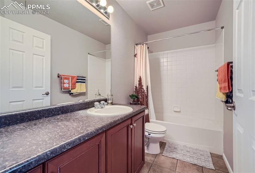 Full bathroom featuring vanity, vinyl floors, toilet, and shower / bath combination with curtain