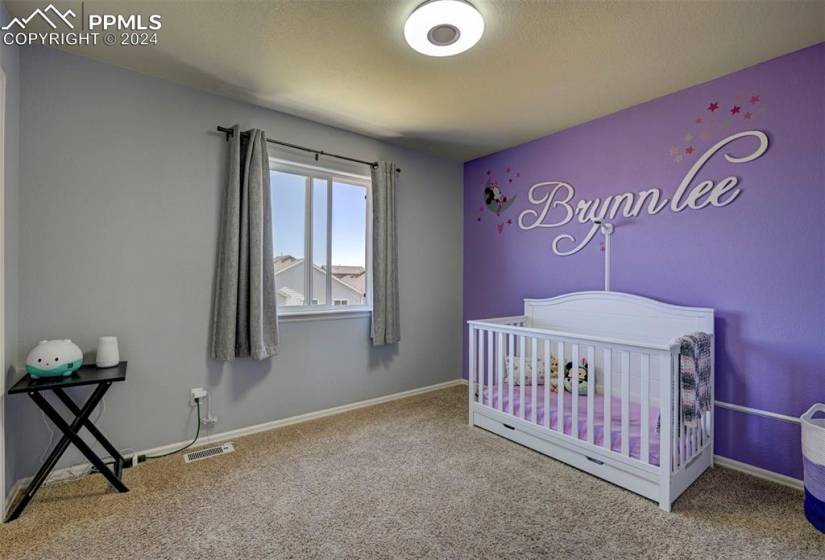 Bedroom featuring a nursery area and light colored carpet