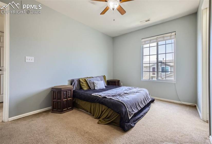 Primary bedroom featuring light colored carpet, lots of natural light, and a ceiling fan