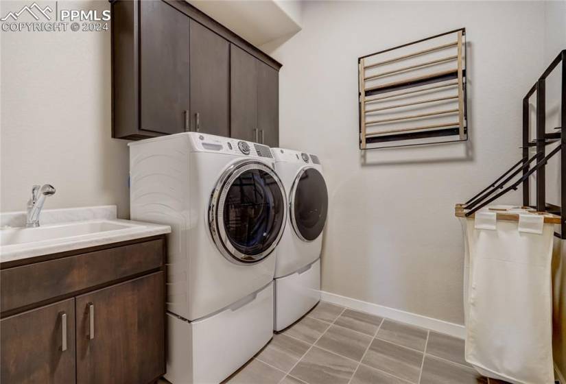Main Level Laundry Room with Utility Sink, Upper + Lower Cabinets and Tile Flooring
