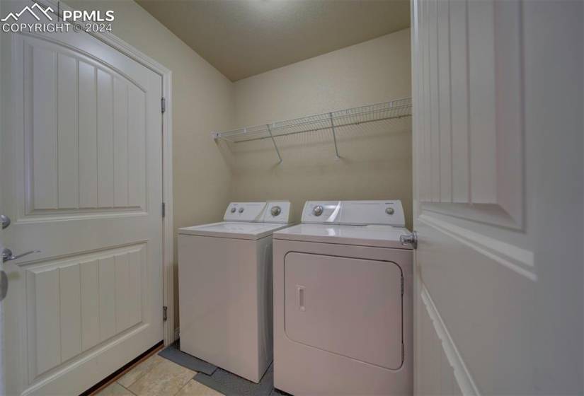 Laundry room featuring washer and clothes dryer and light tile floors off garage
