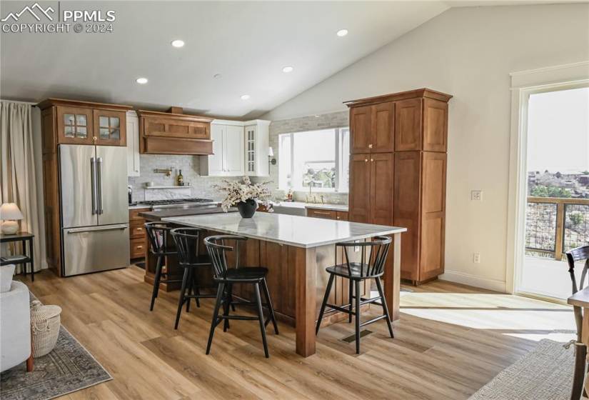 Kitchen featuring appliances with stainless steel finishes, light hardwood / wood-style flooring, plenty of natural light, and premium range hood