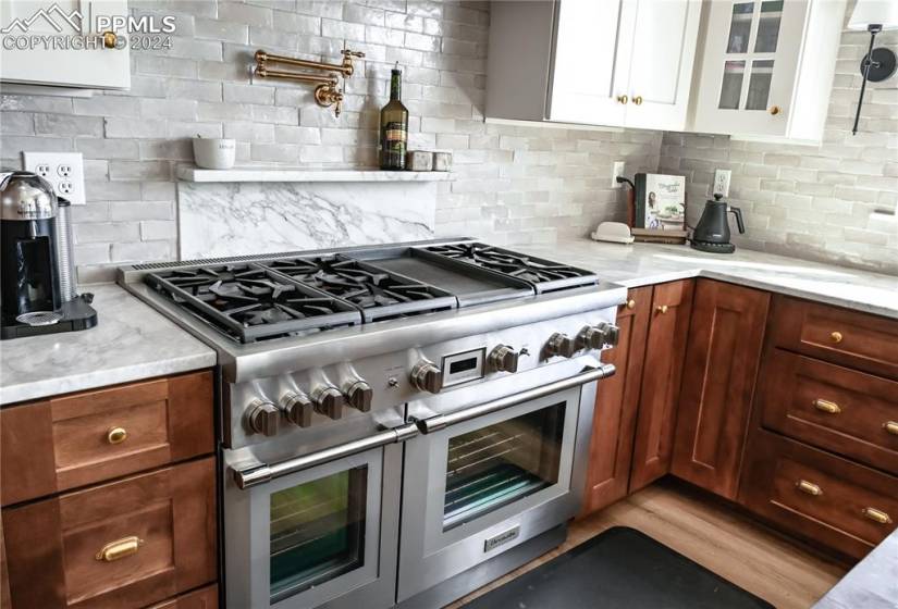 Kitchen with hardwood / wood-style flooring, white cabinets, and tasteful backsplash