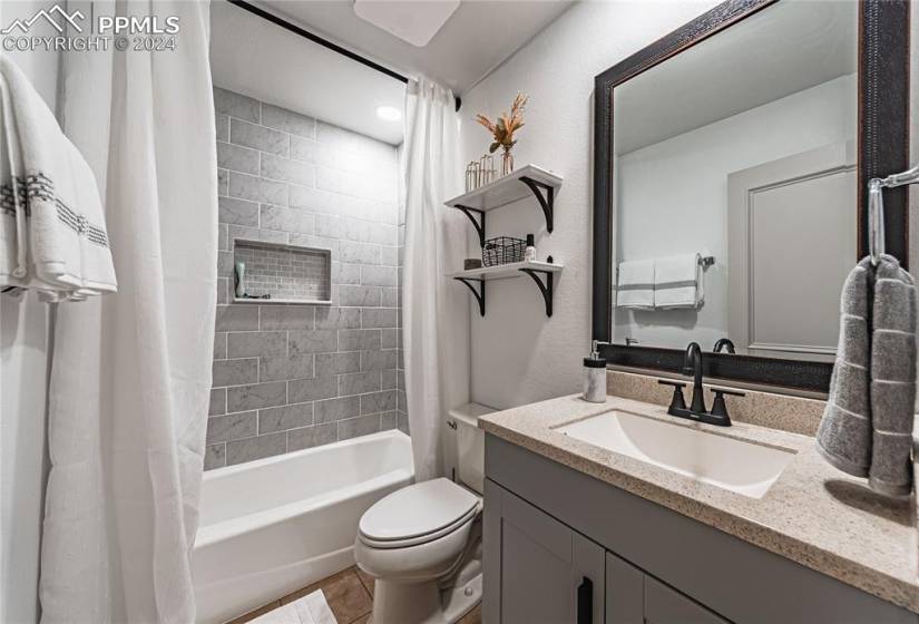 Full bathroom featuring vanity, tile flooring, shower / bath combo with shower curtain, and toilet