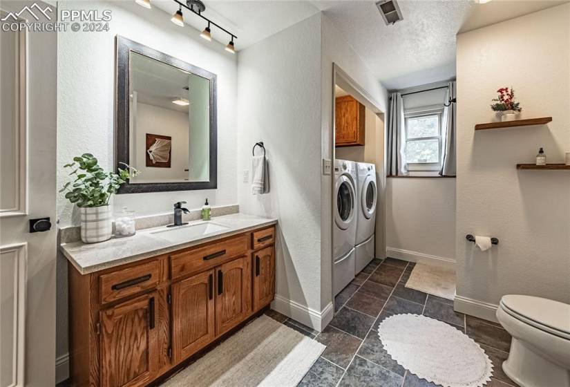 Bathroom with tile floors, a textured ceiling, toilet, separate washer and dryer, and oversized vanity