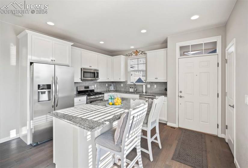 Kitchen featuring a center island, dark wood-type flooring, stainless steel appliances, a kitchen breakfast bar, and white cabinets