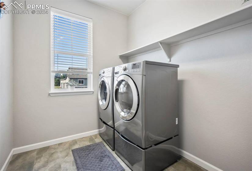 Laundry room featuring light tile floors and washer and clothes dryer