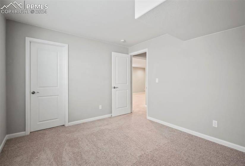 Basement bedroom featuring light colored carpet