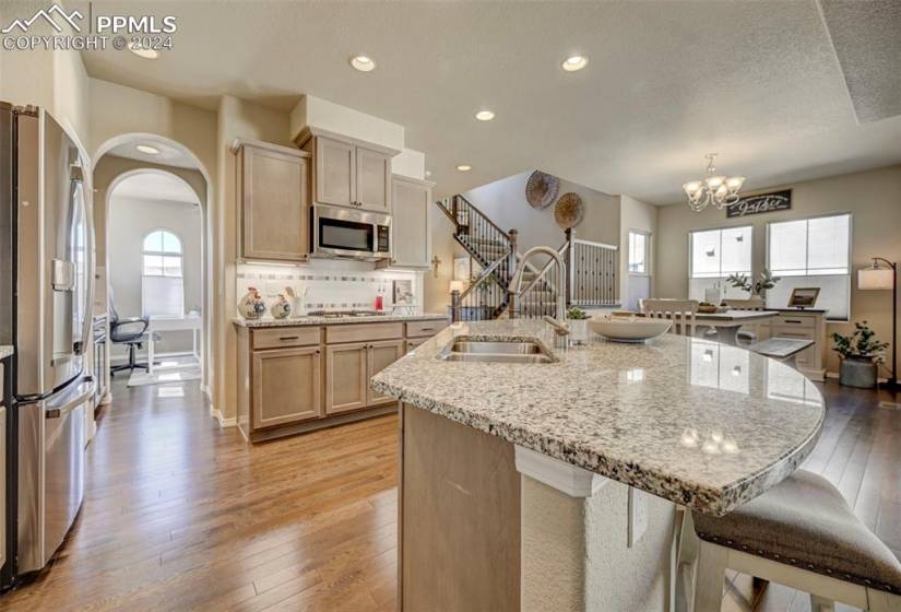 Kitchen featuring a notable chandelier, appliances with stainless steel finishes, a healthy amount of sunlight, and a center island with sink