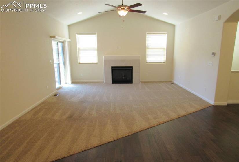 Vaulted living room with gas fireplace and ceiling fan.