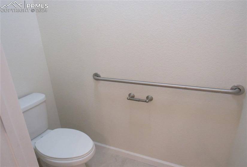 Master bathroom toilet room with tiled floors and grab bars.