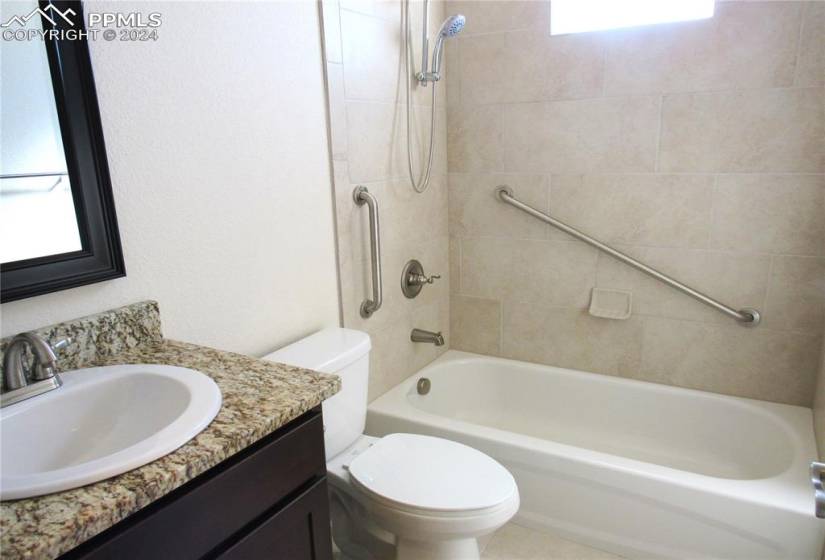 Main-level full bathroom with tiled tub/shower combo and granite countertops. Plenty of natural light