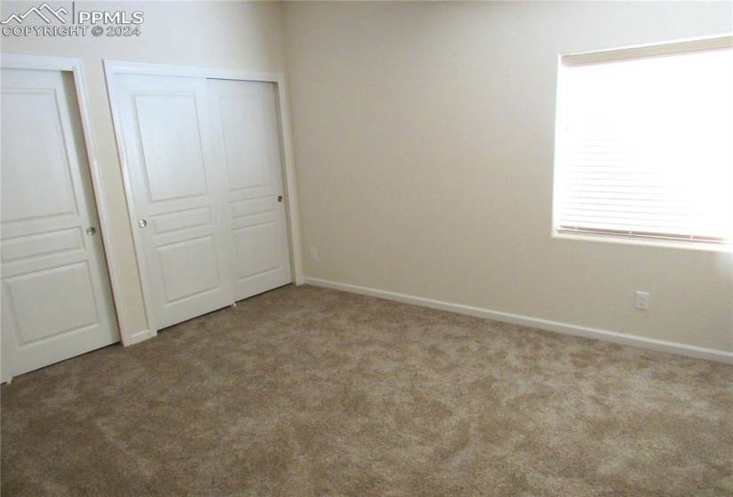 Large basement level bedroom with double closets and carpet.