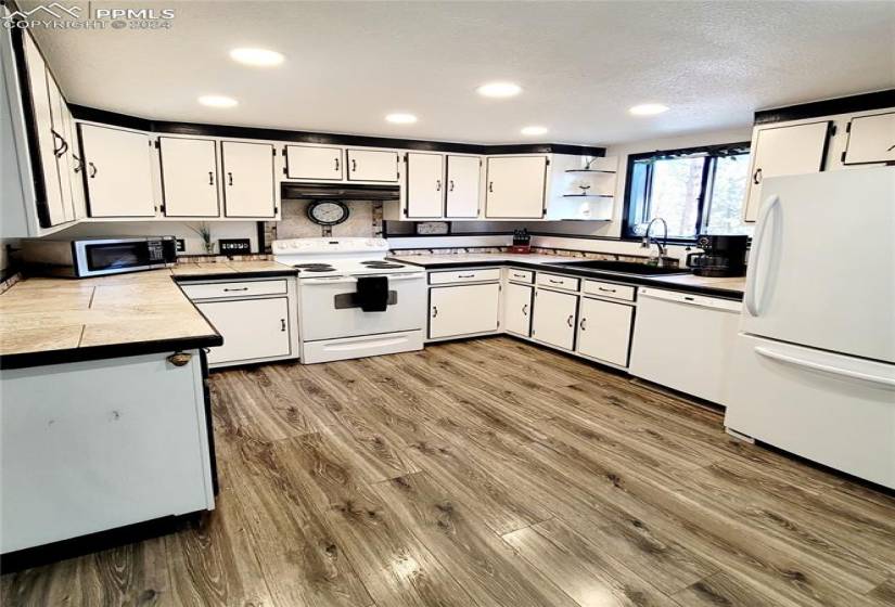 Kitchen featuring white cabinetry, sink, white appliances, and hardwood / wood-style floors