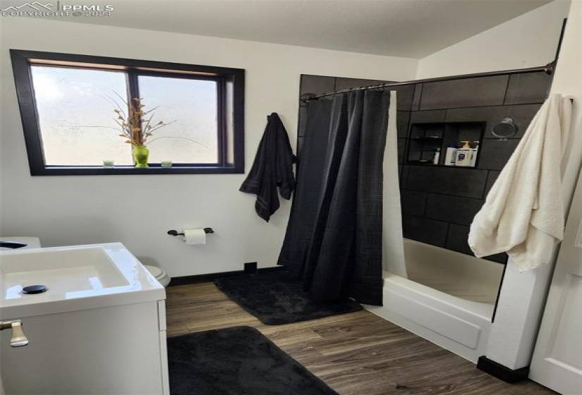 Full bathroom featuring toilet, shower / bath combo with shower curtain, vanity, hardwood / wood-style floors, and lofted ceiling