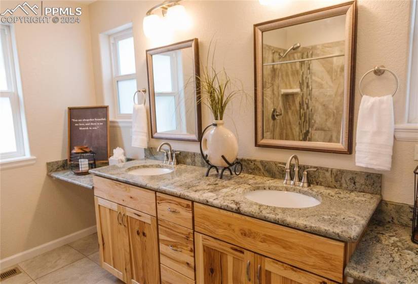 Bathroom with walk in shower, double vanity, tile floors, and a wealth of natural light