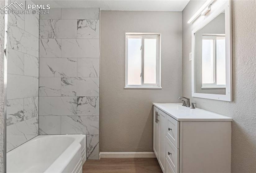 Bathroom featuring tiled shower / bath combo, large vanity, and hardwood / wood-style floors