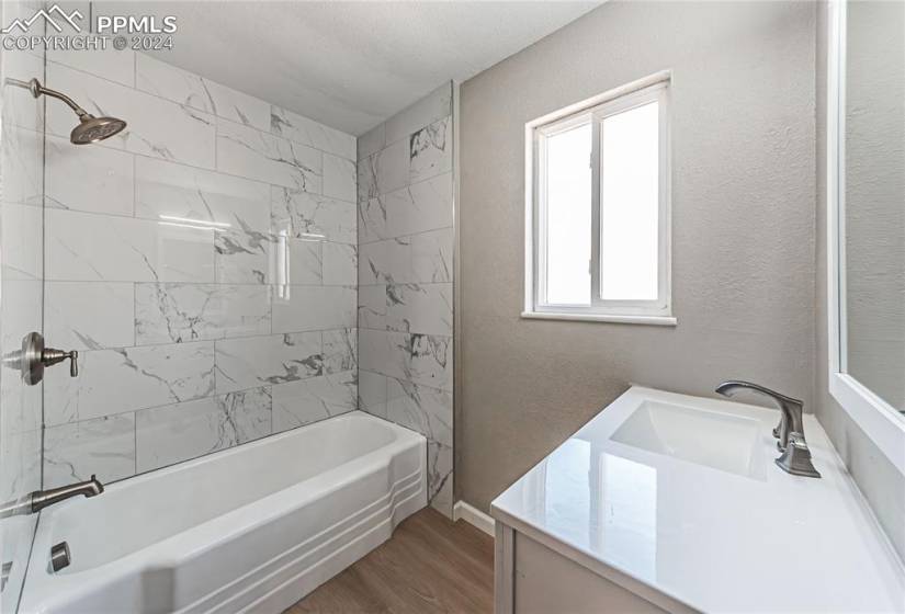 Bathroom with tiled shower / bath, vanity, hardwood / wood-style floors, and plenty of natural light