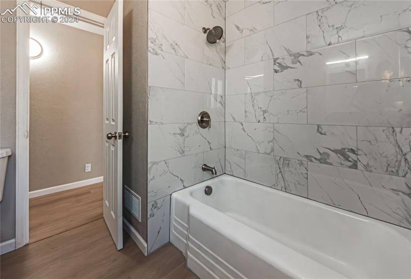 Bathroom with hardwood / wood-style floors and tiled shower / bath