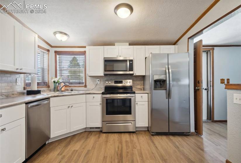 Kitchen w/ corner sink, SS appliances (plumbed for gas stove), LVP flooring