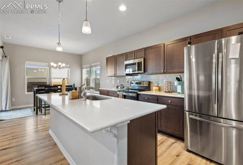 Kitchen featuring hanging light fixtures, light hardwood / wood-style flooring, appliances with stainless steel finishes, and sink