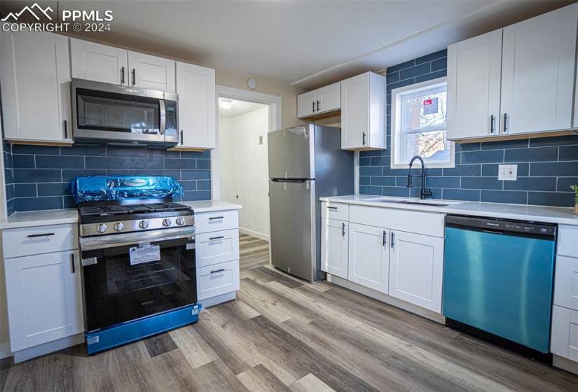 Kitchen featuring sink, stainless steel appliances, backsplash, and light hardwood / wood-style floors