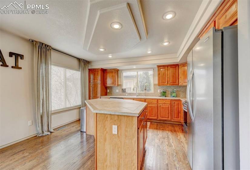 Kitchen with stainless steel refrigerator, a center island, tasteful backsplash, sink, and light hardwood / wood-style flooring