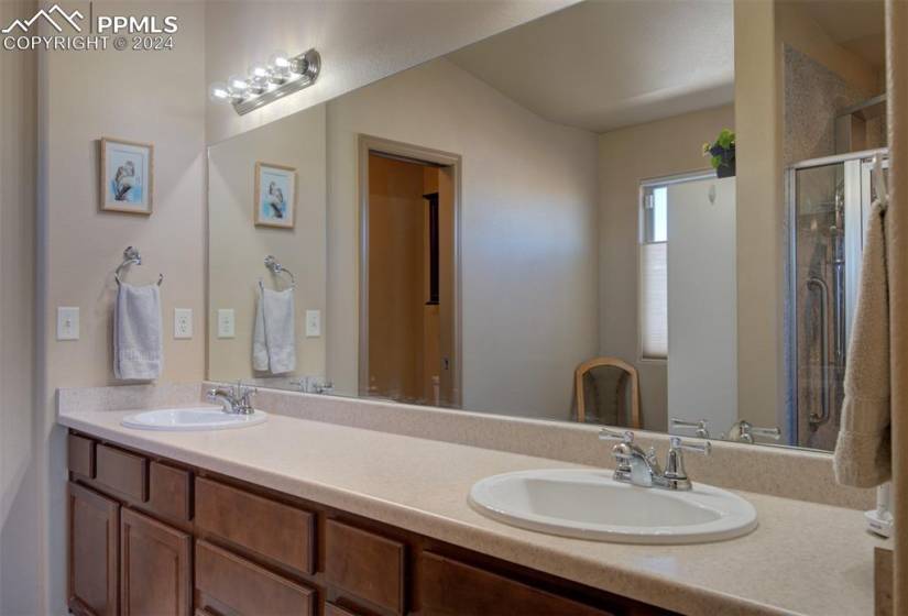 Master Bathroom featuring double vanity with extensive cabinet space, double sink, and an enclosed shower
