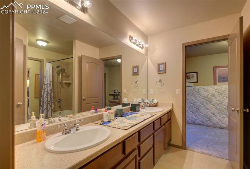 Jack and Jill Bathroom featuring oversized vanity, tile floors, shower / bath combo with shower curtain, and double sink