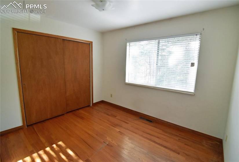 Upper level bedroom with wood flooring and closet