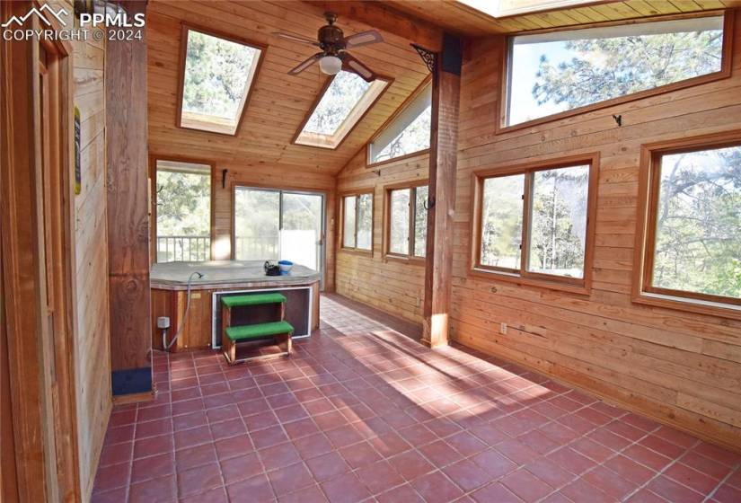 Sunroom off primary bedroom with vaulted ceiling, skylight, ceiling fan, wood ceiling and walks out to deck.