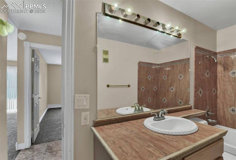 Bathroom with tile floors, vanity, a baseboard radiator, and a textured ceiling