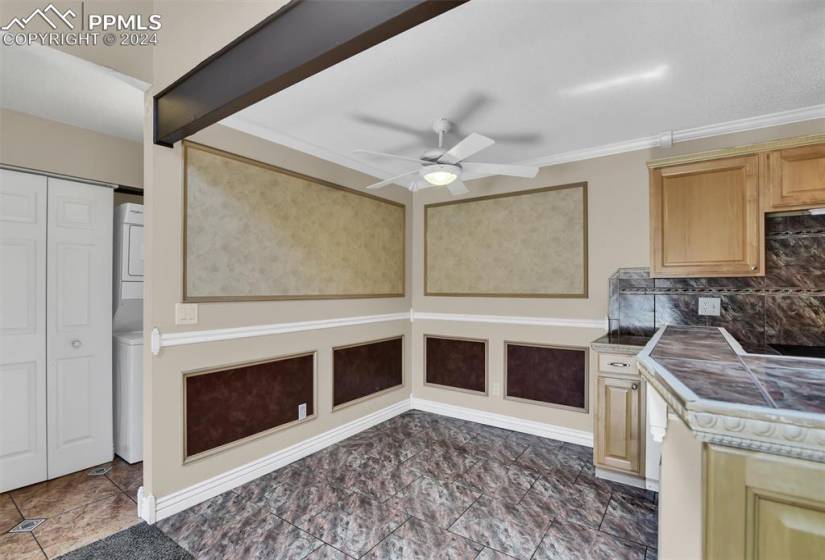 Kitchen with crown molding, backsplash, tile countertops, ceiling fan, and dark tile flooring