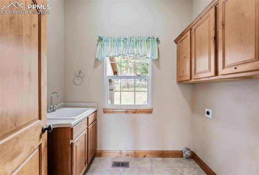 Laundry area featuring sink, hookup for an electric dryer, cabinets, and light tile flooring